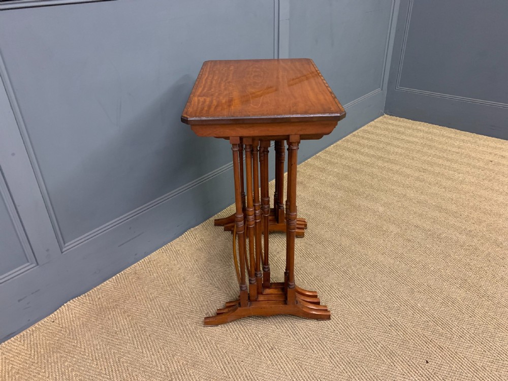 A nest of four graduated wooden tables featuring figure-grained satinwood tops with inlaid borders and slender turned legs. View VI