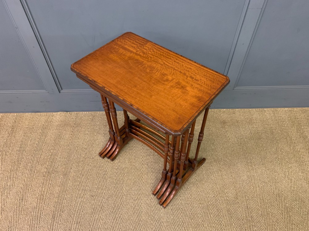 A nest of four graduated wooden tables featuring figure-grained satinwood tops with inlaid borders and slender turned legs. View IX