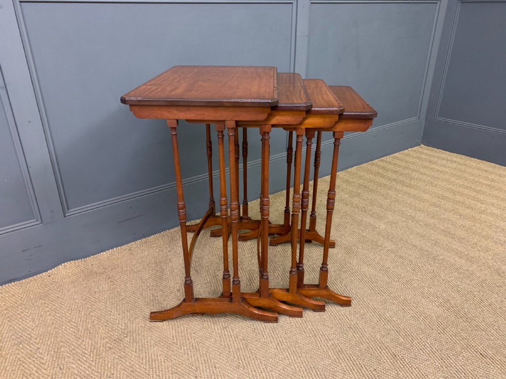 A nest of four graduated wooden tables featuring figure-grained satinwood tops with inlaid borders and slender turned legs. View XI
