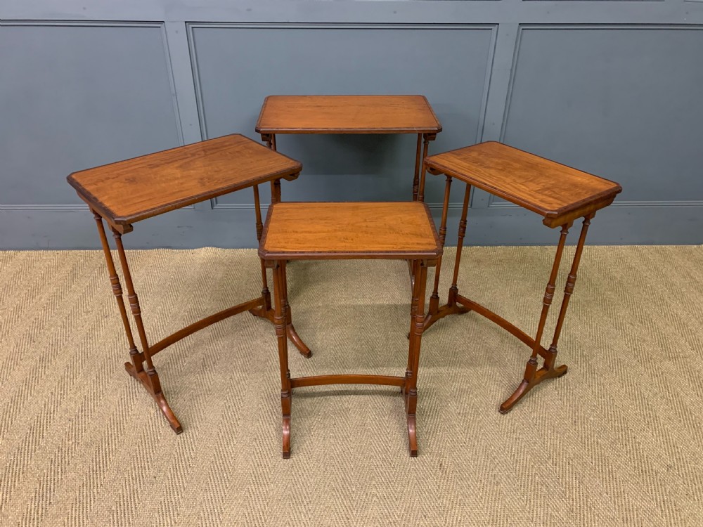 A nest of four graduated wooden tables featuring figure-grained satinwood tops with inlaid borders and slender turned legs. View XIII