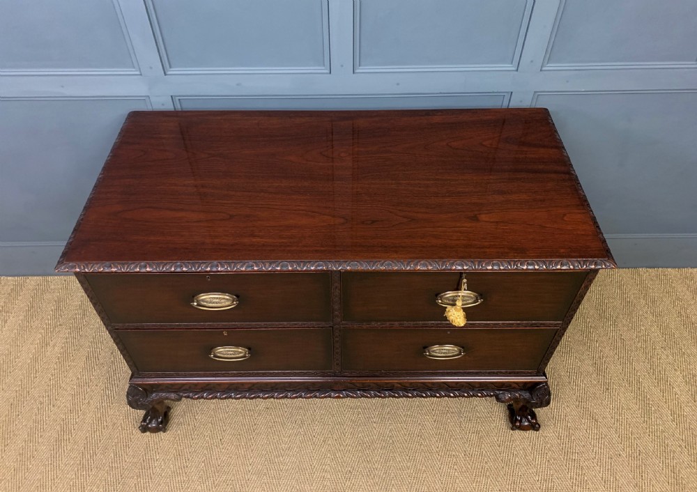 A wide dark mahogany Chippendale style chest featuring four drawers with oval brass handles, carved frieze detailing, and carved ball-and-claw feet. View III