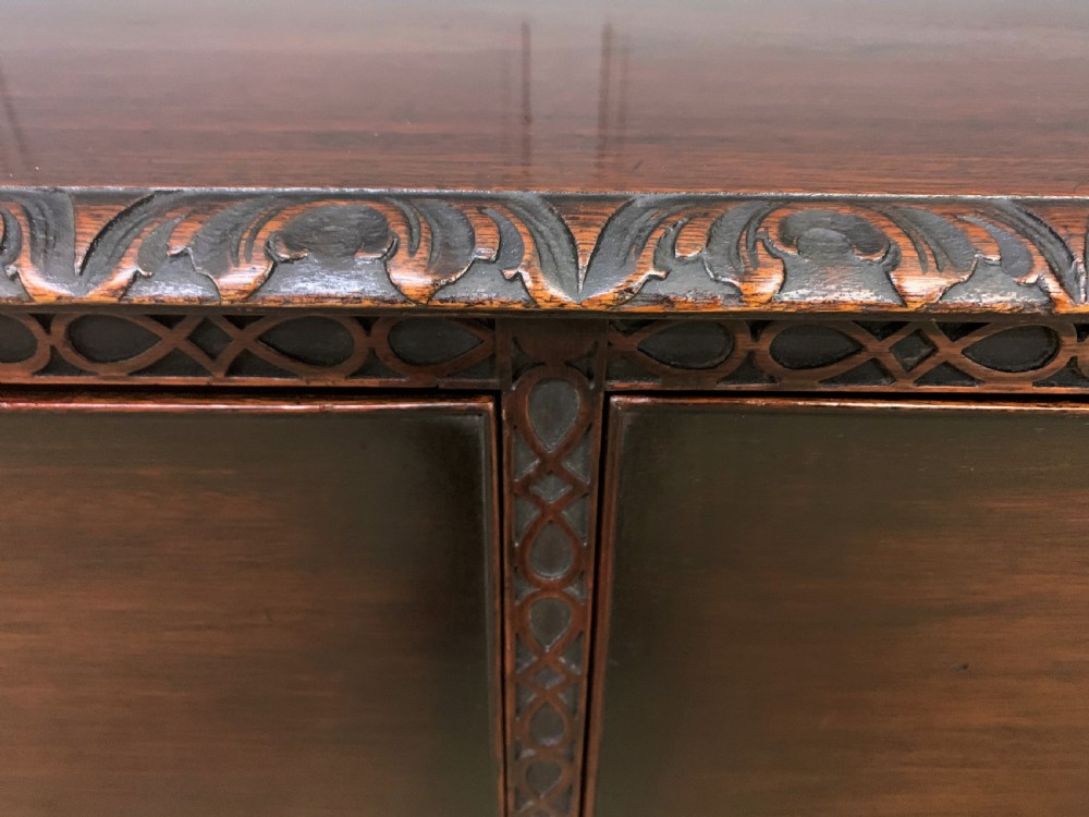 A wide dark mahogany Chippendale style chest featuring four drawers with oval brass handles, carved frieze detailing, and carved ball-and-claw feet. View VI
