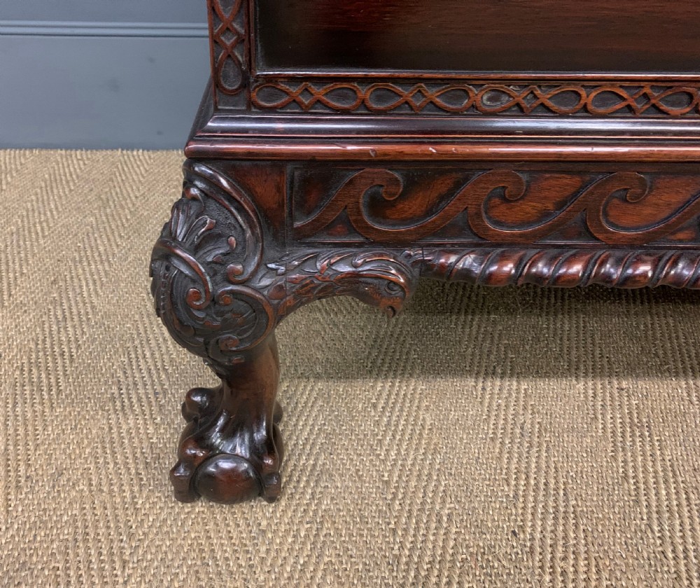 A wide dark mahogany Chippendale style chest featuring four drawers with oval brass handles, carved frieze detailing, and carved ball-and-claw feet. View VIII
