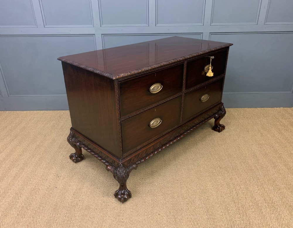 A wide dark mahogany Chippendale style chest featuring four drawers with oval brass handles, carved frieze detailing, and carved ball-and-claw feet. View XII