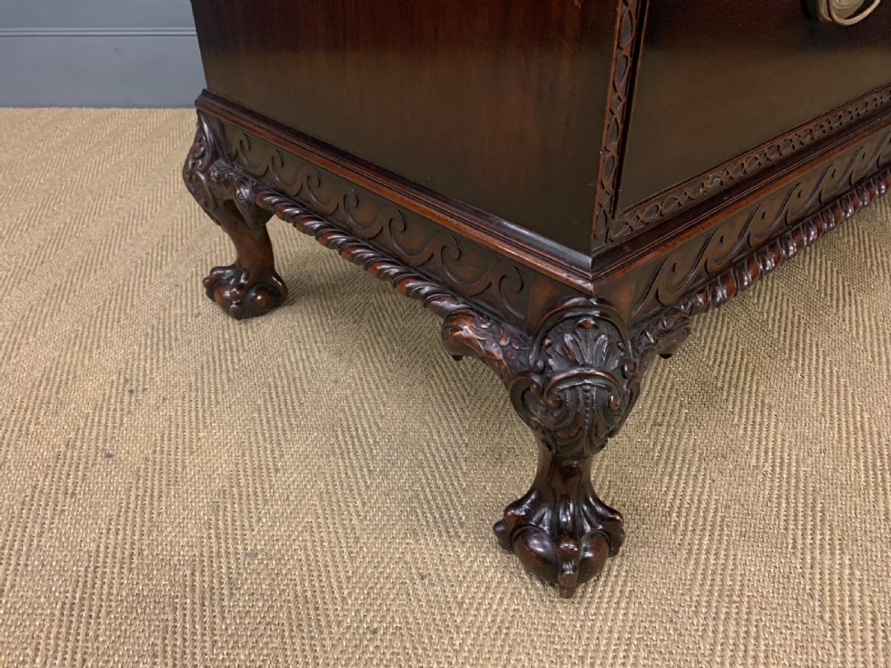 A wide dark mahogany Chippendale style chest featuring four drawers with oval brass handles, carved frieze detailing, and carved ball-and-claw feet. View XIII