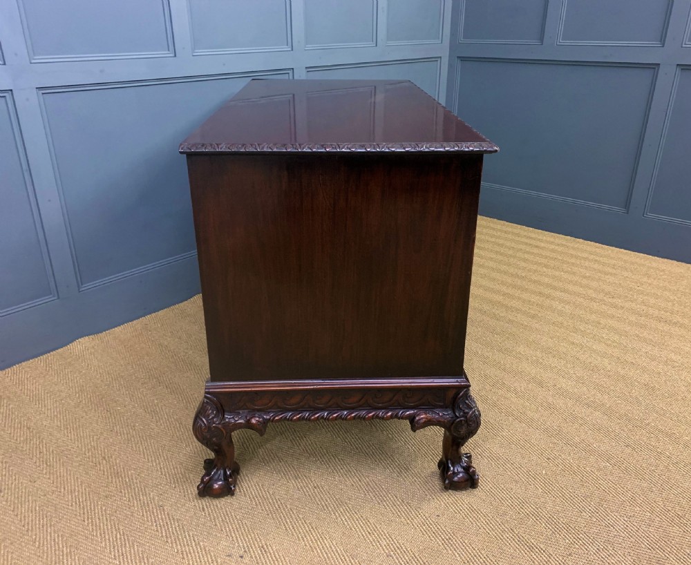 A wide dark mahogany Chippendale style chest featuring four drawers with oval brass handles, carved frieze detailing, and carved ball-and-claw feet. View XIV
