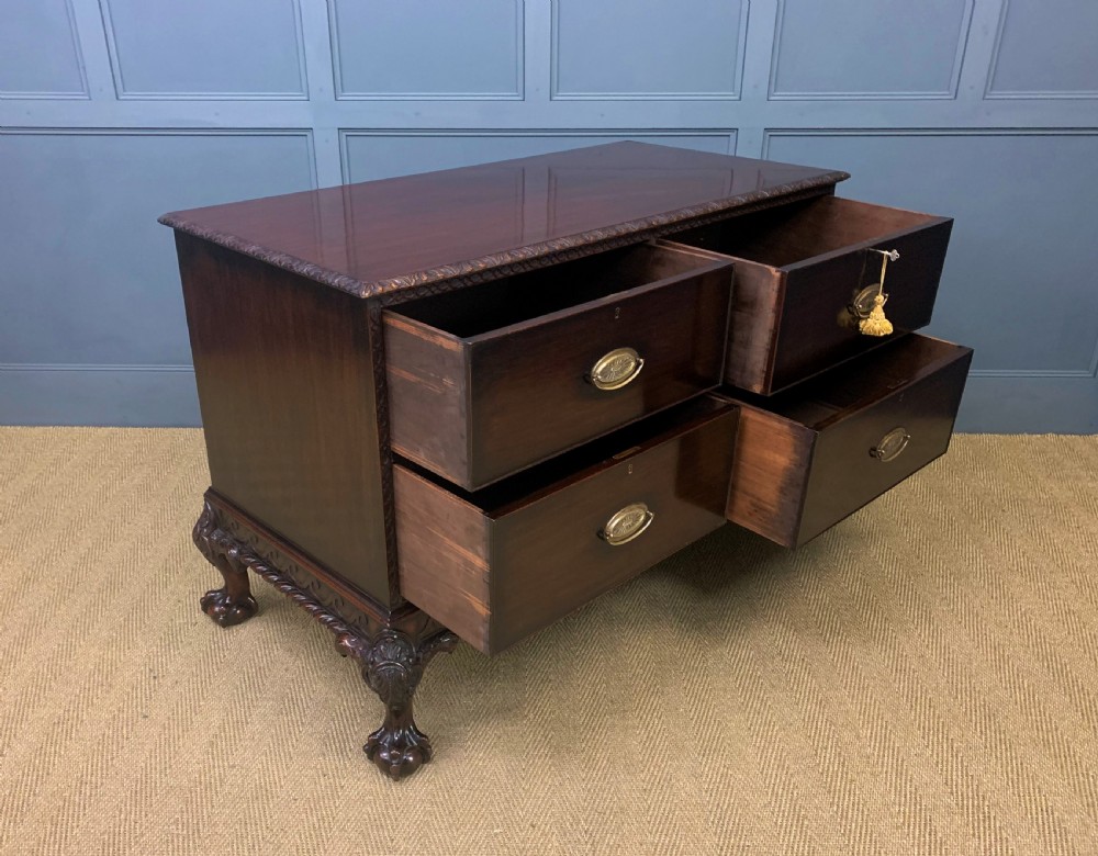 A wide dark mahogany Chippendale style chest featuring four drawers with oval brass handles, carved frieze detailing, and carved ball-and-claw feet. View XV