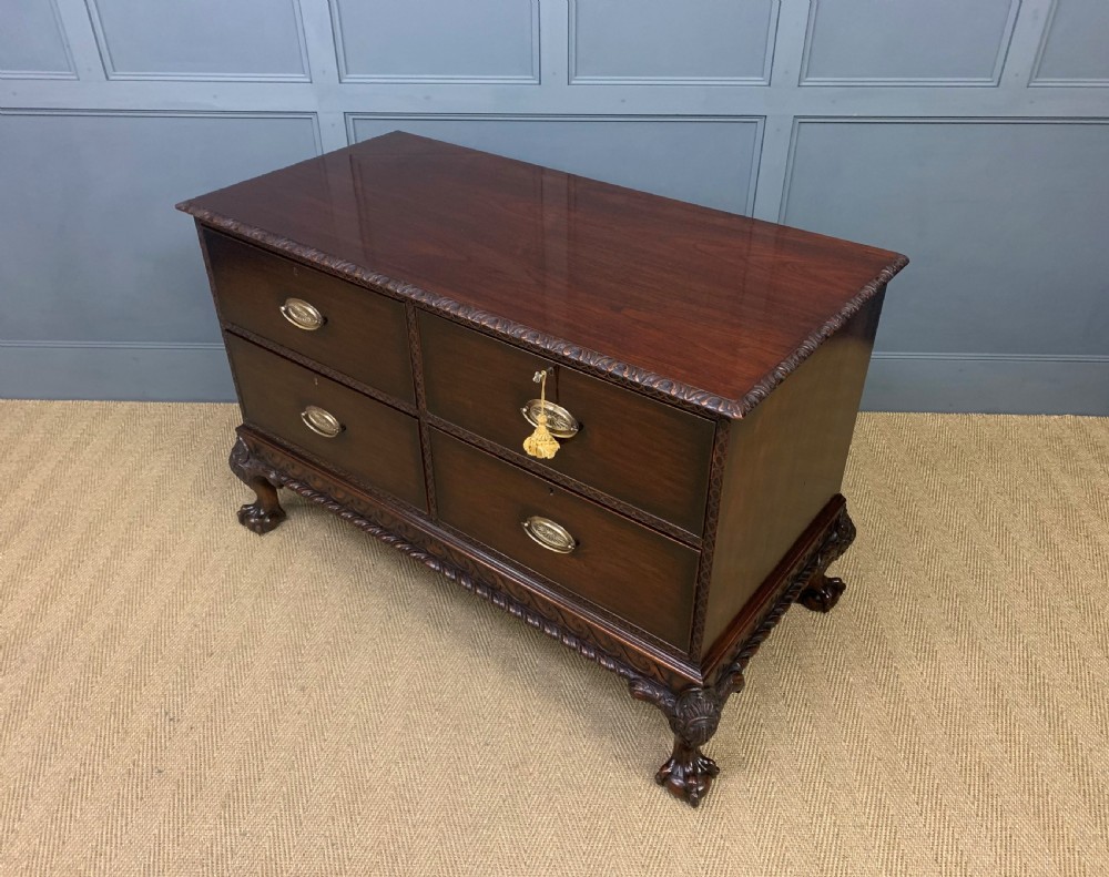 A wide dark mahogany Chippendale style chest featuring four drawers with oval brass handles, carved frieze detailing, and carved ball-and-claw feet. View XVI