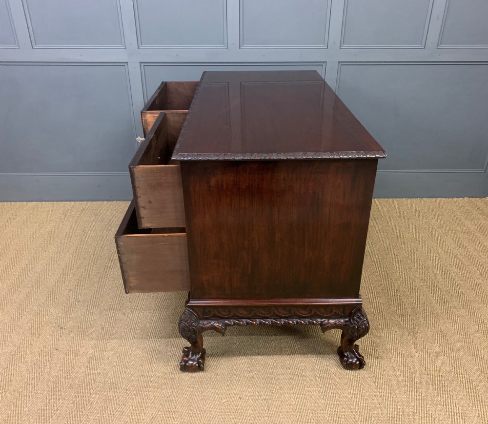 A wide dark mahogany Chippendale style chest featuring four drawers with oval brass handles, carved frieze detailing, and carved ball-and-claw feet. View XVII