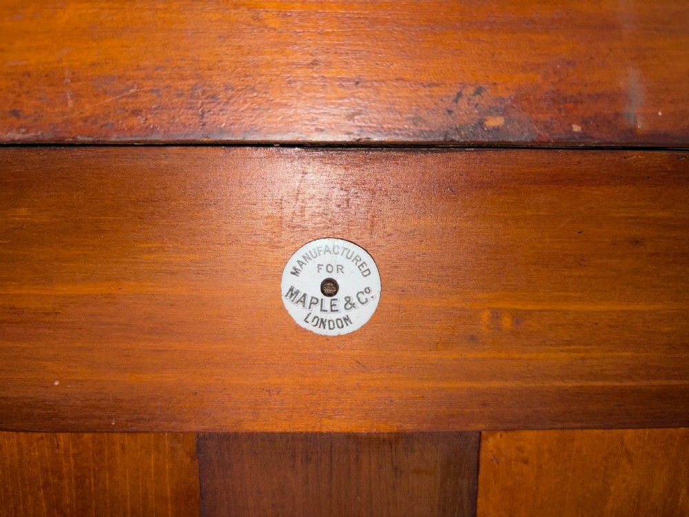 An Edwardian inlaid satinwood display cabinet featuring a central glazed door with an oval wood frame, fabric-lined shelves, and tapered square legs. View II