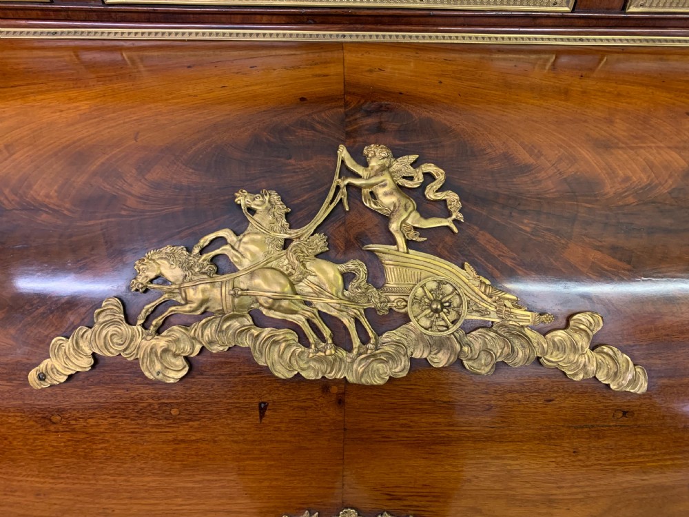A nineteenth-century French Empire flame mahogany cylinder desk featuring a pink marble top, ornate gilt bronze mounts, and carved winged lion feet. View II
