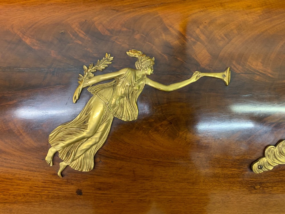 A nineteenth-century French Empire flame mahogany cylinder desk featuring a pink marble top, ornate gilt bronze mounts, and carved winged lion feet. View III