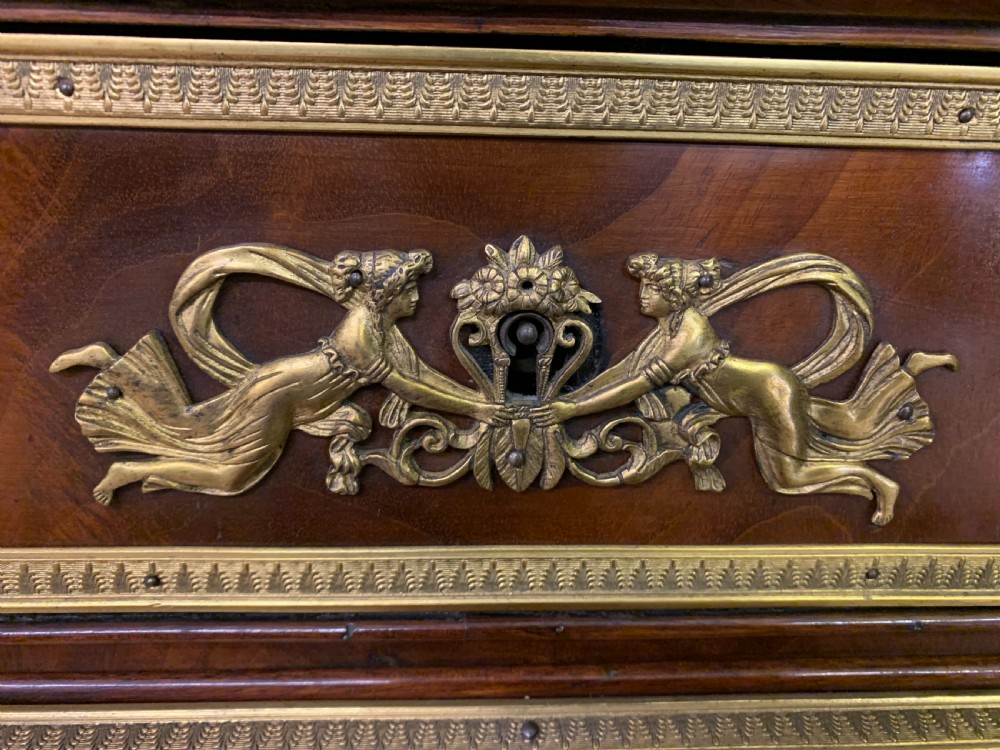 A nineteenth-century French Empire flame mahogany cylinder desk featuring a pink marble top, ornate gilt bronze mounts, and carved winged lion feet. View VI
