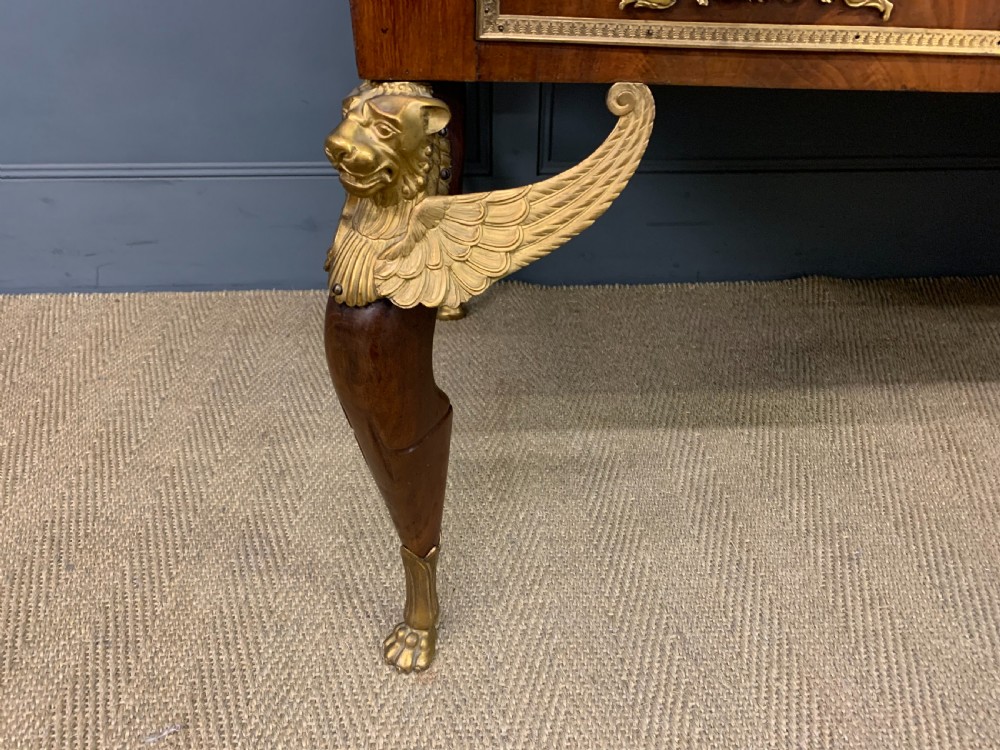 A nineteenth-century French Empire flame mahogany cylinder desk featuring a pink marble top, ornate gilt bronze mounts, and carved winged lion feet. View XI
