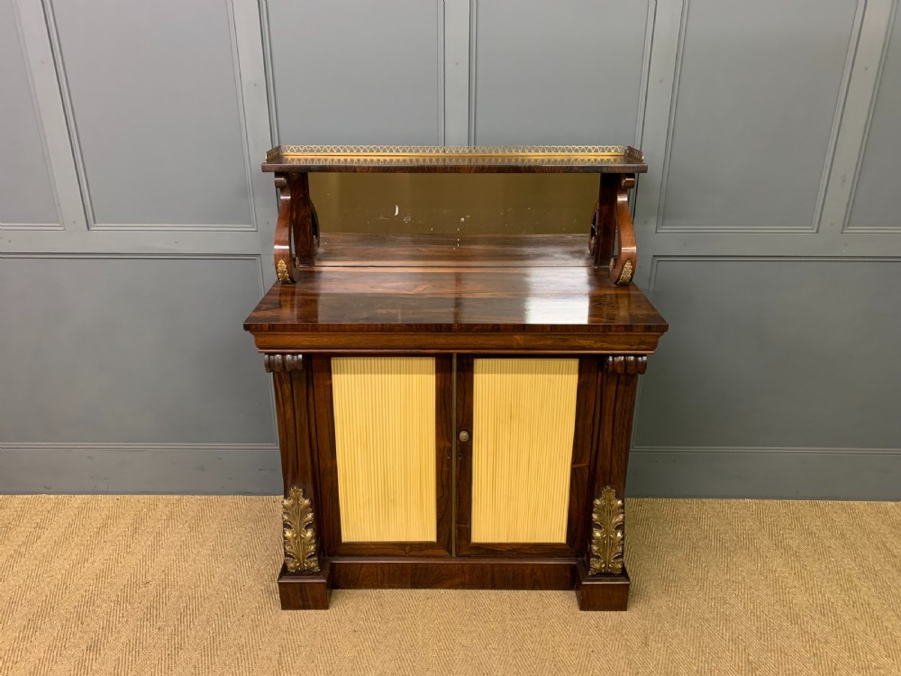 A Regency rosewood chiffonier cabinet featuring a top shelf with a brass gallery on S-scroll supports over a two-door cupboard with pleated yellow fabric panels. View III
