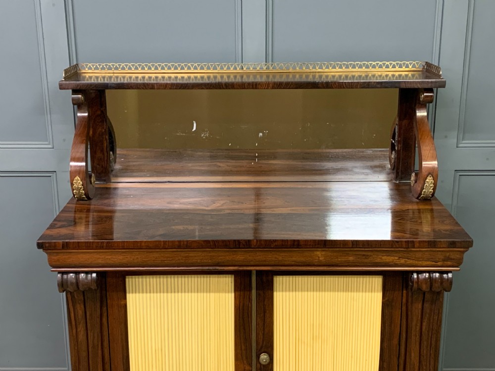 A Regency rosewood chiffonier cabinet featuring a top shelf with a brass gallery on S-scroll supports over a two-door cupboard with pleated yellow fabric panels. View IV