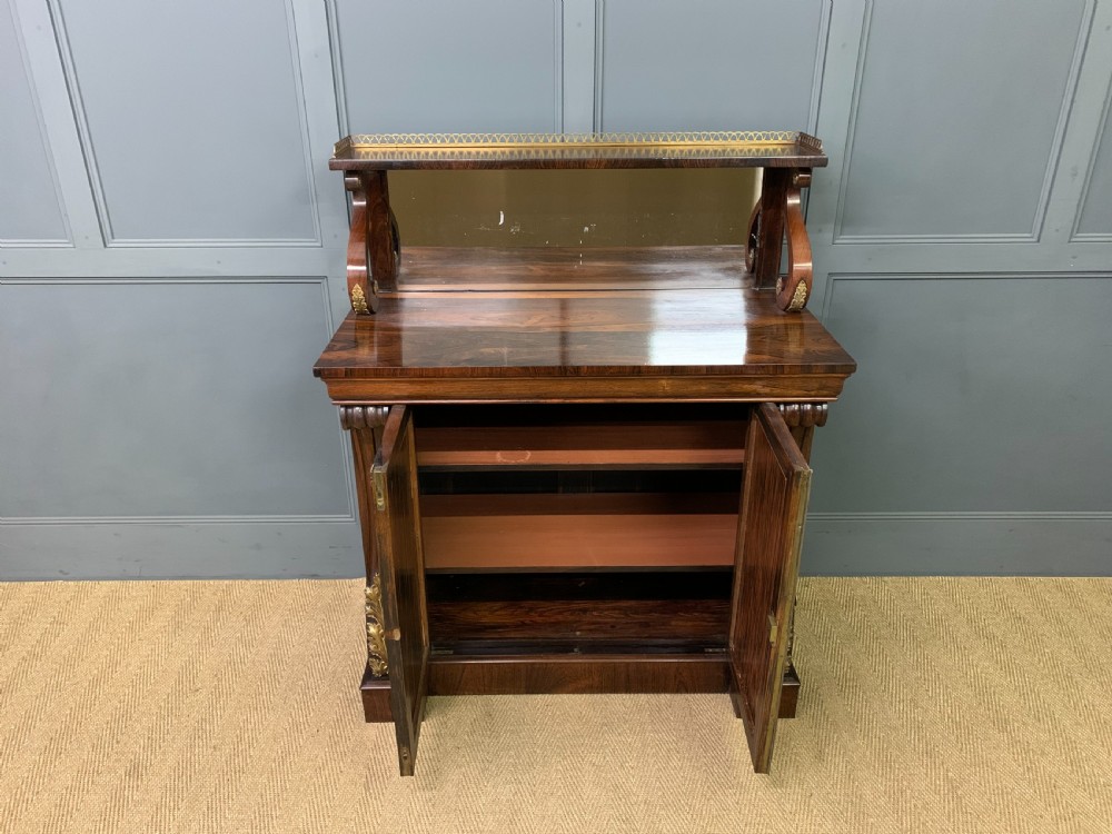 A Regency rosewood chiffonier cabinet featuring a top shelf with a brass gallery on S-scroll supports over a two-door cupboard with pleated yellow fabric panels. View VI