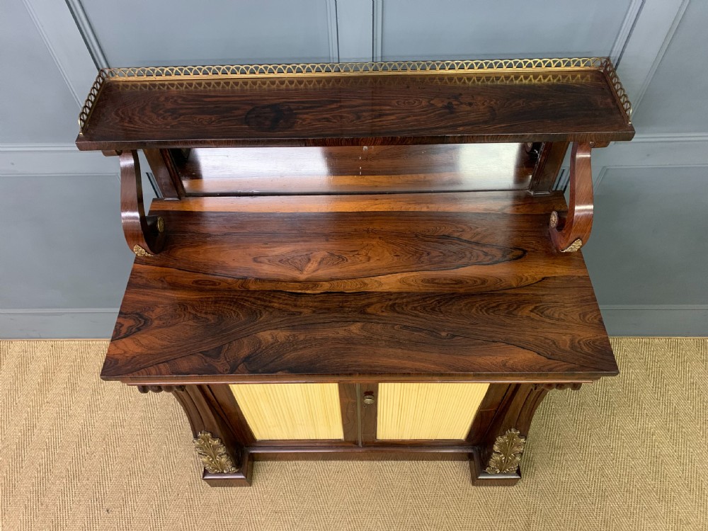 A Regency rosewood chiffonier cabinet featuring a top shelf with a brass gallery on S-scroll supports over a two-door cupboard with pleated yellow fabric panels. View VII