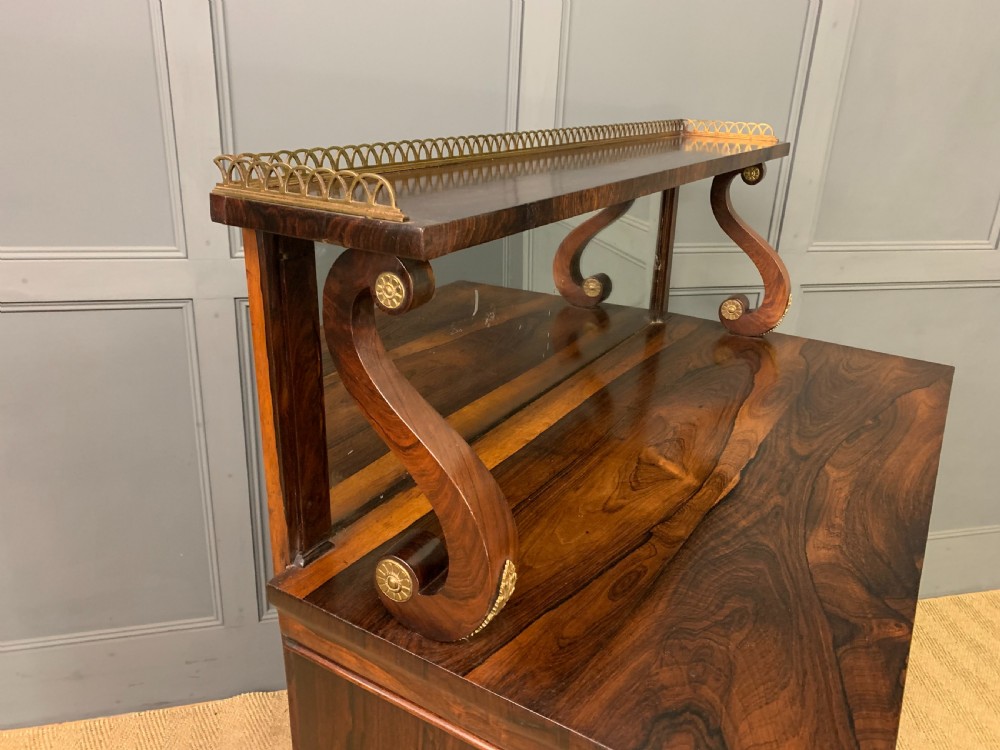 A Regency rosewood chiffonier cabinet featuring a top shelf with a brass gallery on S-scroll supports over a two-door cupboard with pleated yellow fabric panels. View XI
