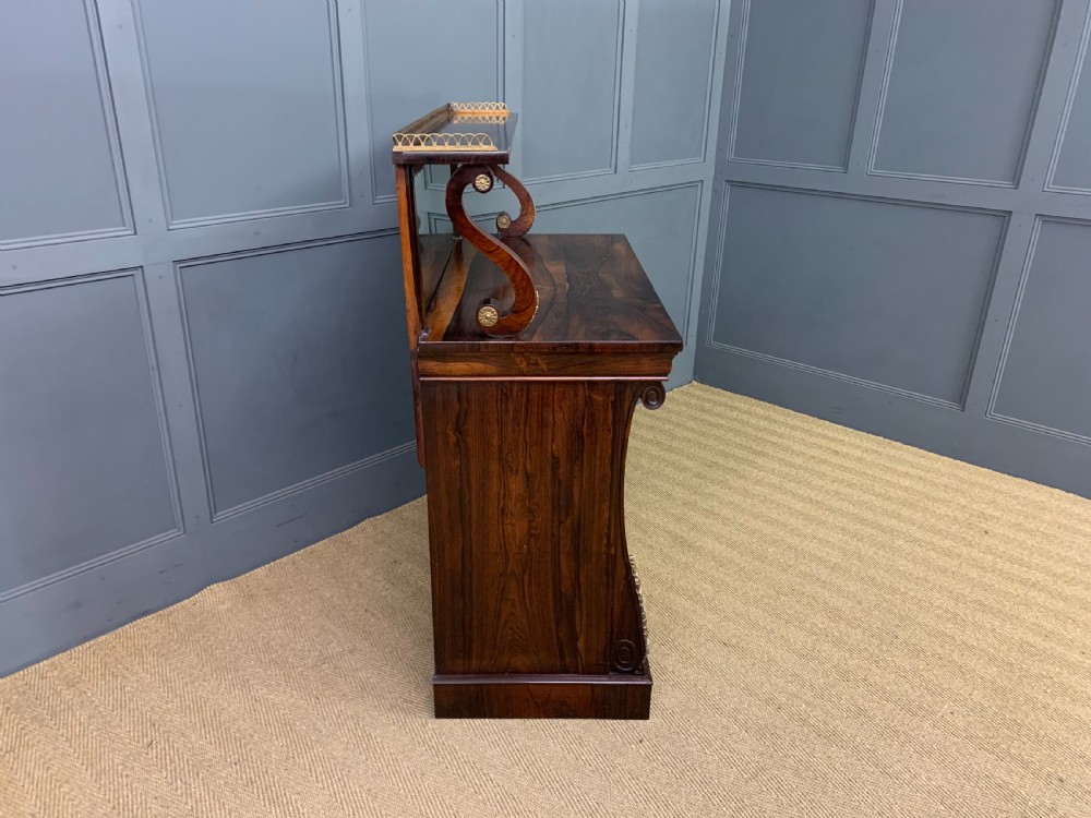 A Regency rosewood chiffonier cabinet featuring a top shelf with a brass gallery on S-scroll supports over a two-door cupboard with pleated yellow fabric panels. View XIV