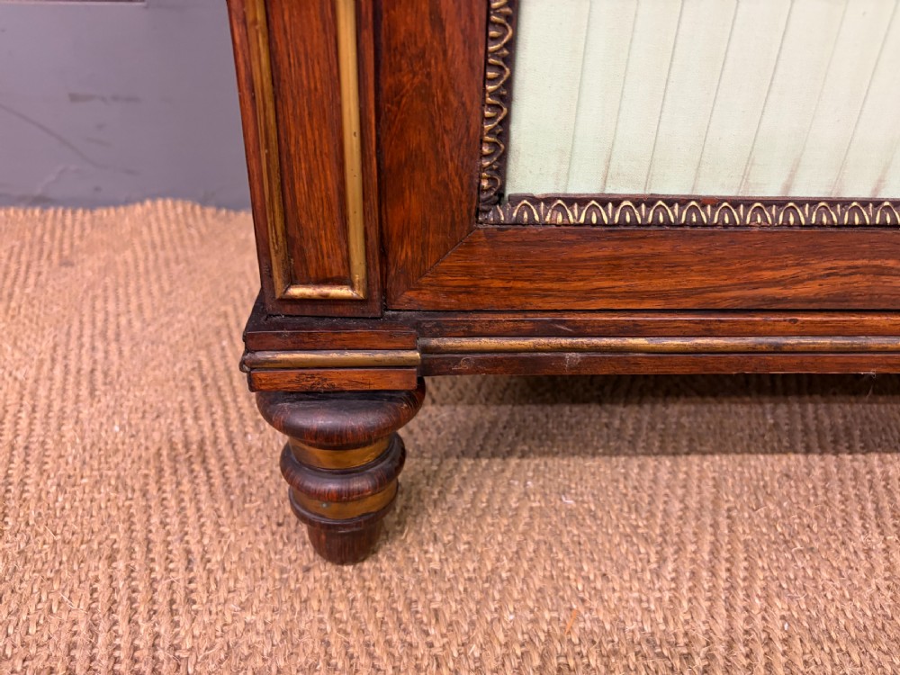 A pair of Regency period rosewood side cabinets featuring brass galleries, raised upper shelves, and pleated light green fabric door panels. View VI