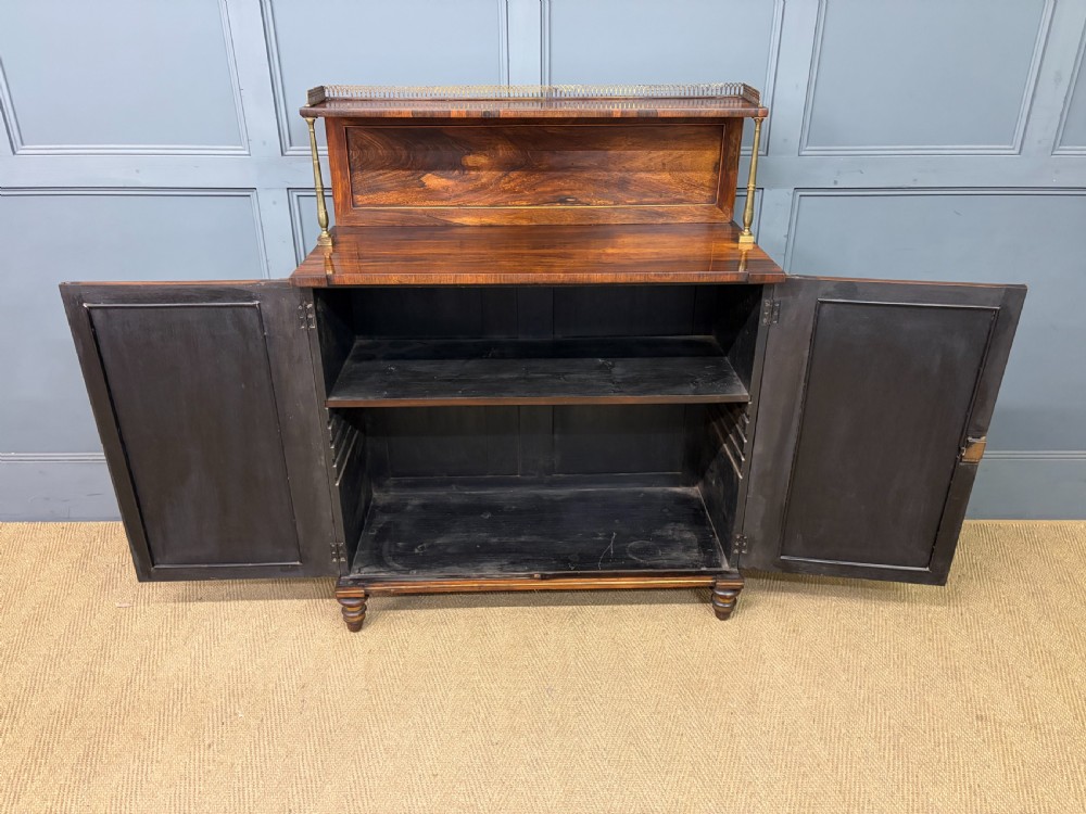 A pair of Regency period rosewood side cabinets featuring brass galleries, raised upper shelves, and pleated light green fabric door panels. View IX