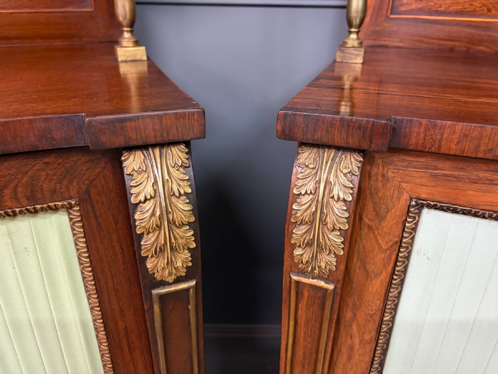 A pair of Regency period rosewood side cabinets featuring brass galleries, raised upper shelves, and pleated light green fabric door panels. View XII
