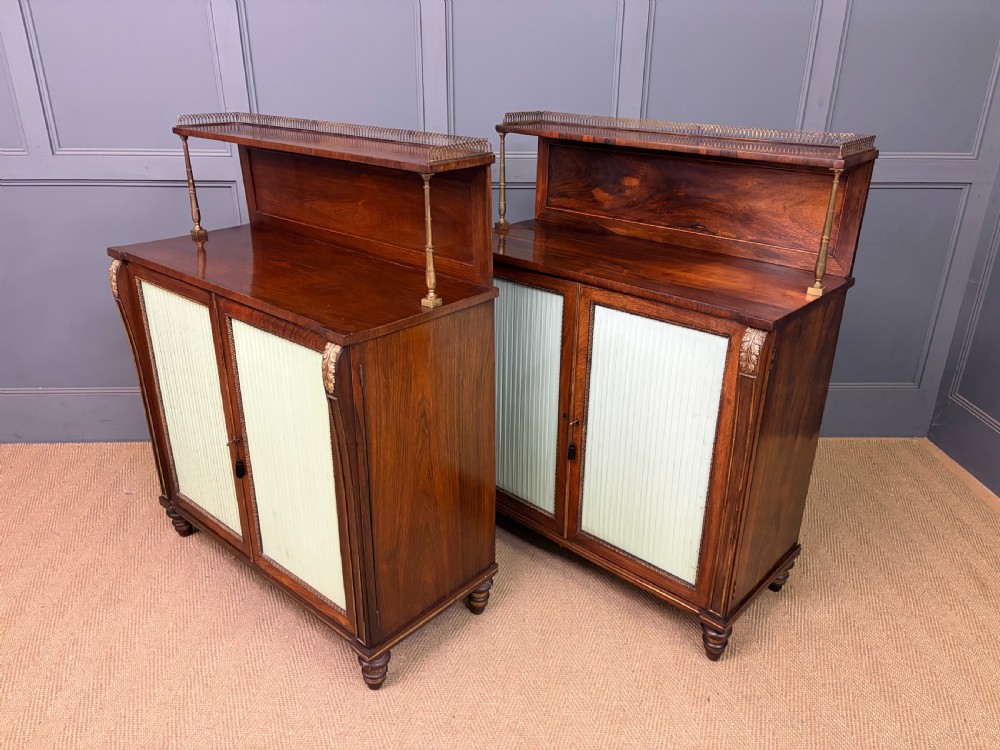 A pair of Regency period rosewood side cabinets featuring brass galleries, raised upper shelves, and pleated light green fabric door panels. View XIV