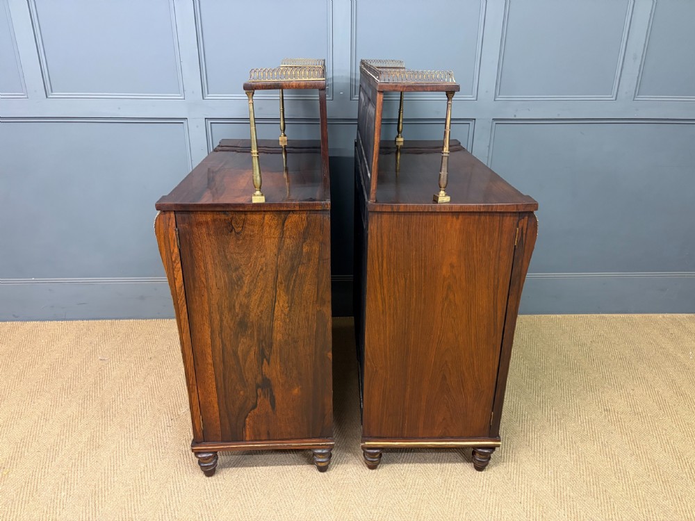 A pair of Regency period rosewood side cabinets featuring brass galleries, raised upper shelves, and pleated light green fabric door panels. View XV