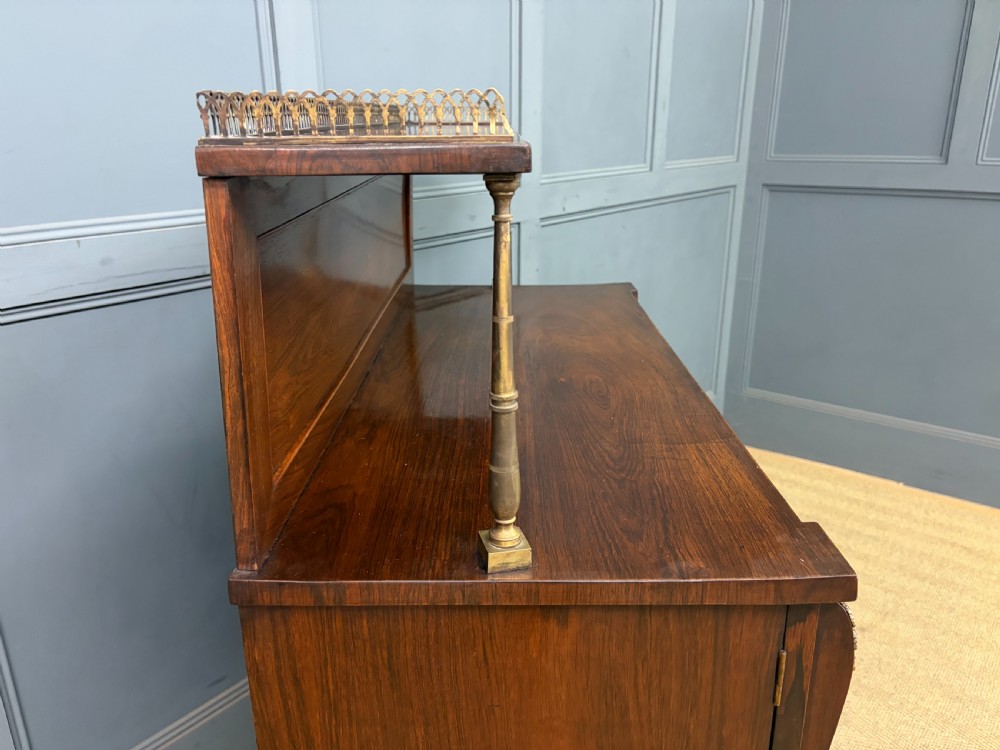 A pair of Regency period rosewood side cabinets featuring brass galleries, raised upper shelves, and pleated light green fabric door panels. View XVIII