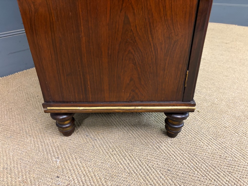 A pair of Regency period rosewood side cabinets featuring brass galleries, raised upper shelves, and pleated light green fabric door panels. View XIX