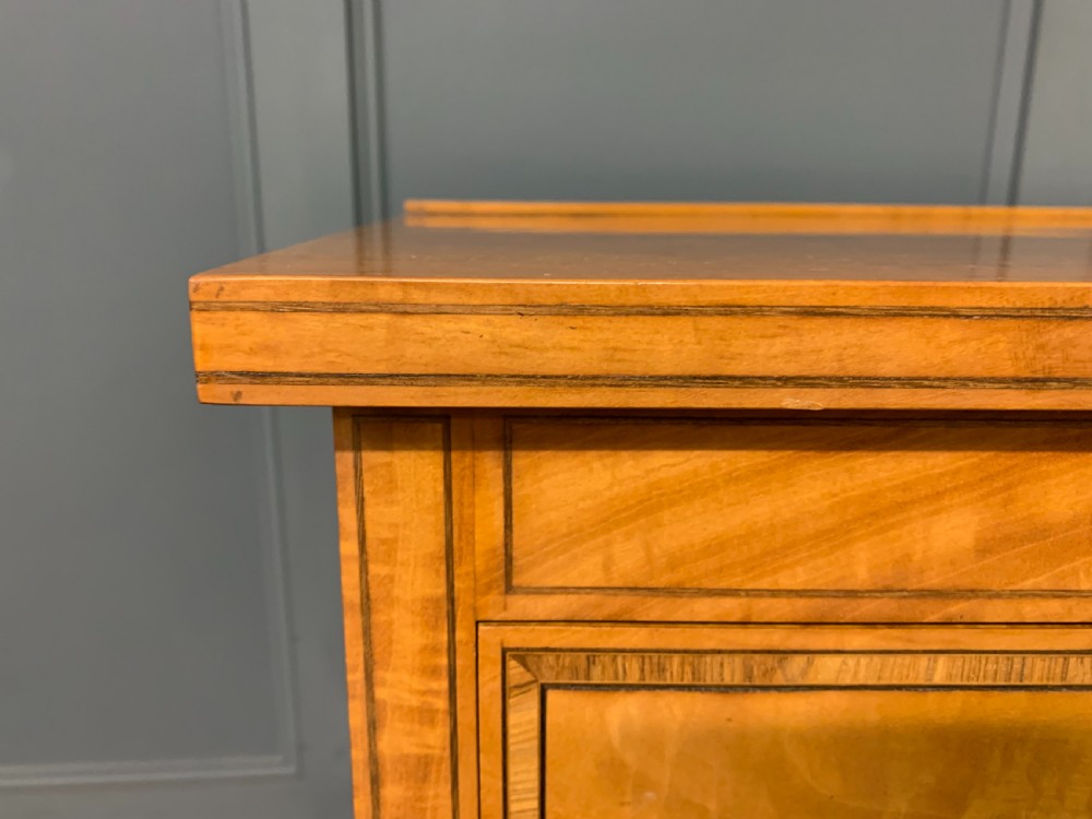 A tall satinwood chest of drawers featuring eight inlaid drawers with brass swan-neck handles and bracket feet. View XIII