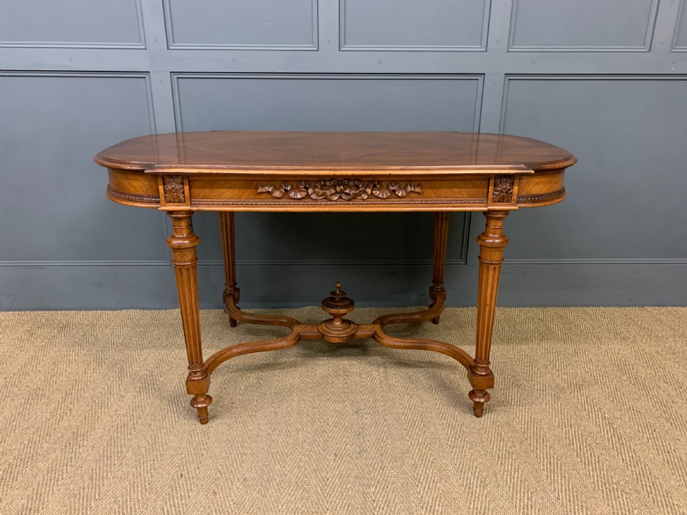 A 19th-century French walnut centre table featuring a parquet veneered top, carved floral frieze, fluted turned legs, and a shaped X-stretcher with a central finial. View II