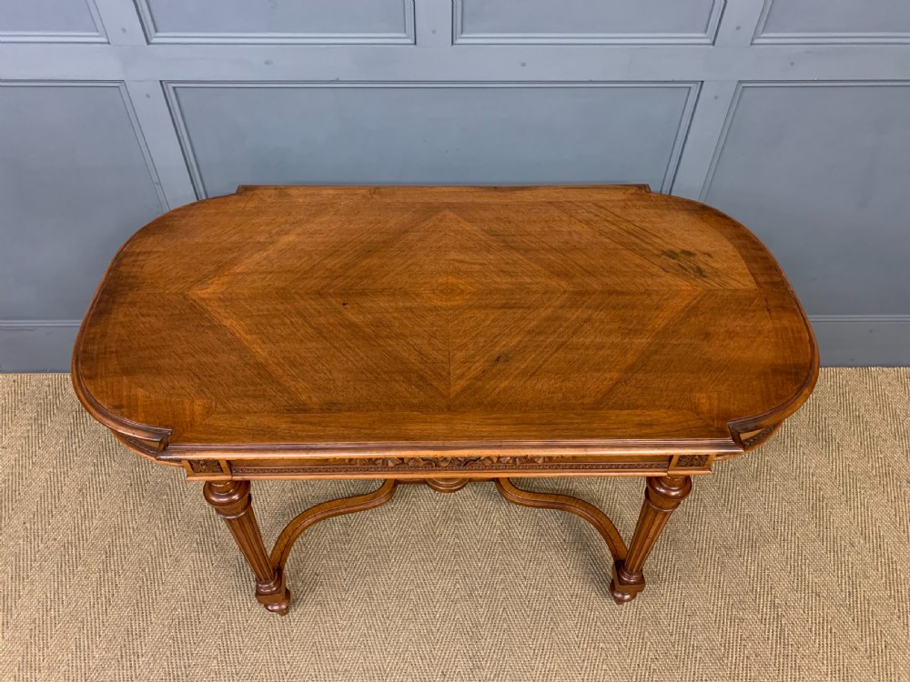 A 19th-century French walnut centre table featuring a parquet veneered top, carved floral frieze, fluted turned legs, and a shaped X-stretcher with a central finial. View III