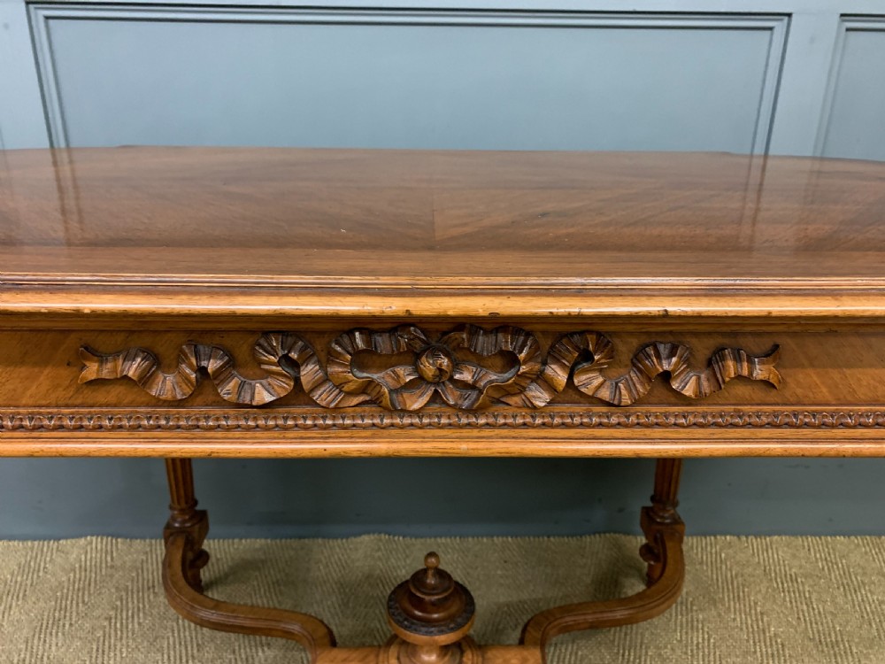 A 19th-century French walnut centre table featuring a parquet veneered top, carved floral frieze, fluted turned legs, and a shaped X-stretcher with a central finial. View IV