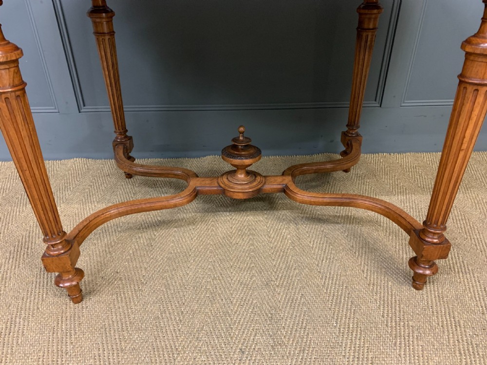 A 19th-century French walnut centre table featuring a parquet veneered top, carved floral frieze, fluted turned legs, and a shaped X-stretcher with a central finial. View VI