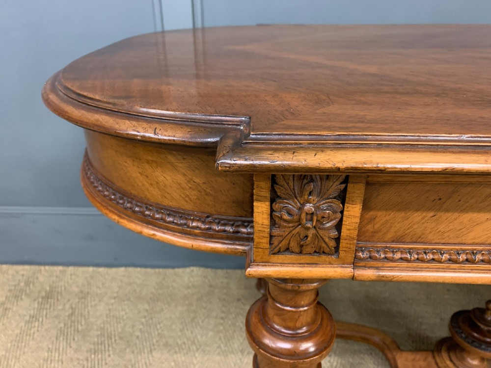 A 19th-century French walnut centre table featuring a parquet veneered top, carved floral frieze, fluted turned legs, and a shaped X-stretcher with a central finial. View VII