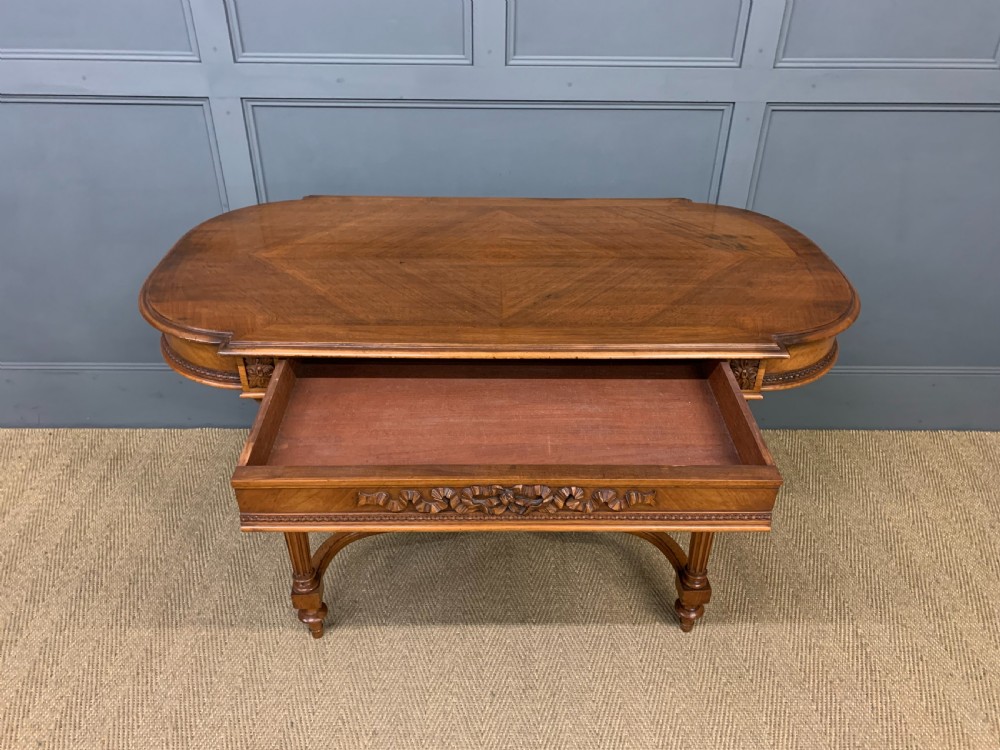 A 19th-century French walnut centre table featuring a parquet veneered top, carved floral frieze, fluted turned legs, and a shaped X-stretcher with a central finial. View VIII