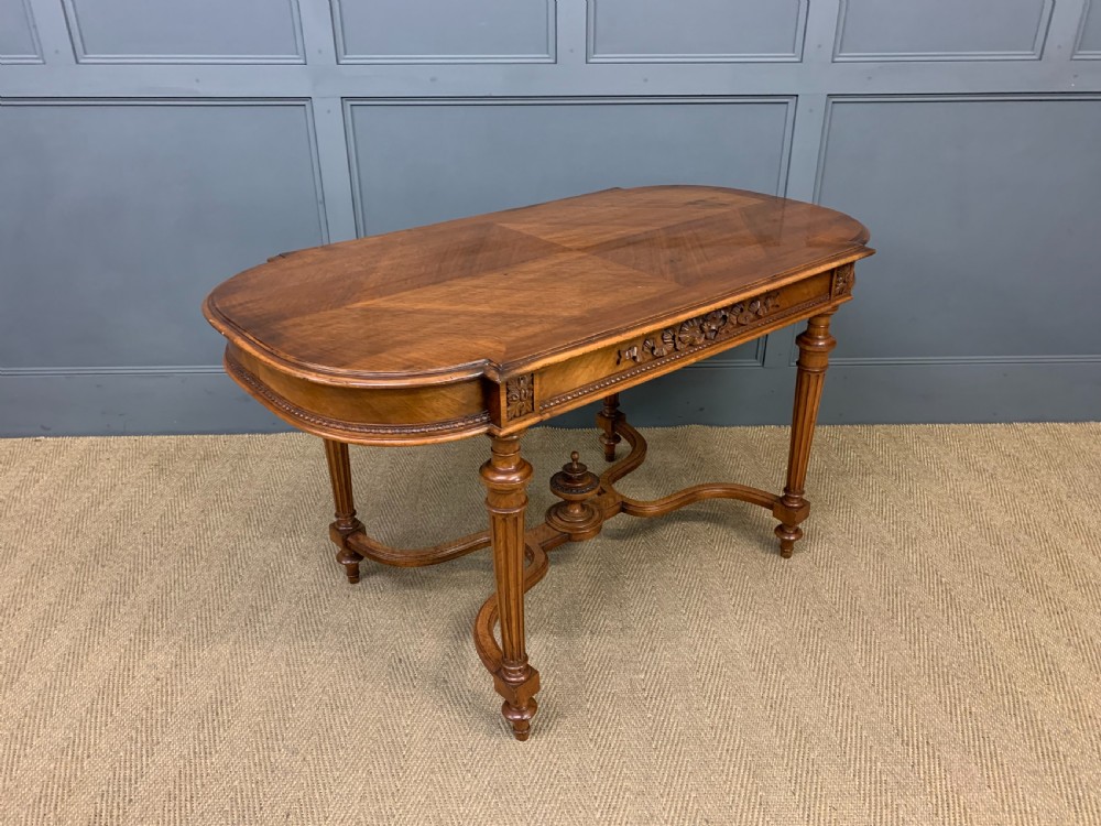 A 19th-century French walnut centre table featuring a parquet veneered top, carved floral frieze, fluted turned legs, and a shaped X-stretcher with a central finial. View IX
