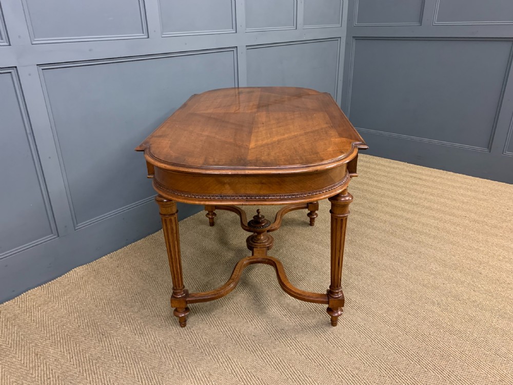 A 19th-century French walnut centre table featuring a parquet veneered top, carved floral frieze, fluted turned legs, and a shaped X-stretcher with a central finial. View X