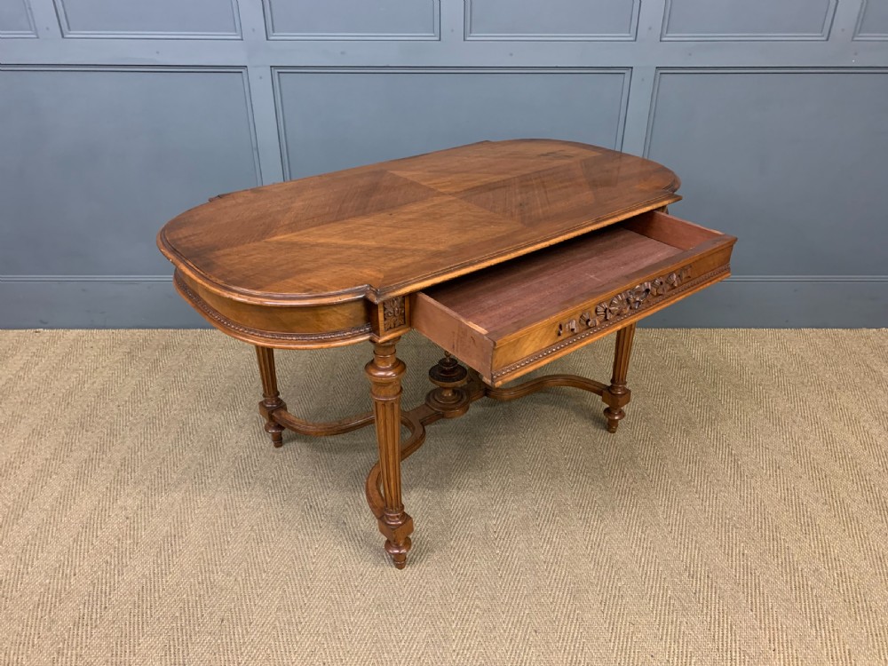 A 19th-century French walnut centre table featuring a parquet veneered top, carved floral frieze, fluted turned legs, and a shaped X-stretcher with a central finial. View XII