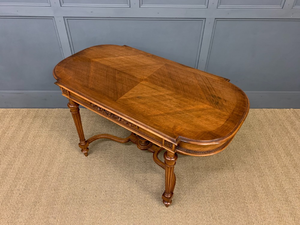 A 19th-century French walnut centre table featuring a parquet veneered top, carved floral frieze, fluted turned legs, and a shaped X-stretcher with a central finial. View XIII