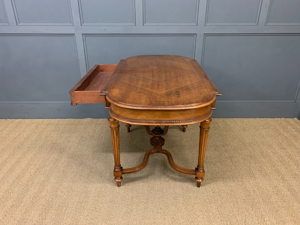 A 19th-century French walnut centre table featuring a parquet veneered top, carved floral frieze, fluted turned legs, and a shaped X-stretcher with a central finial. View XIV