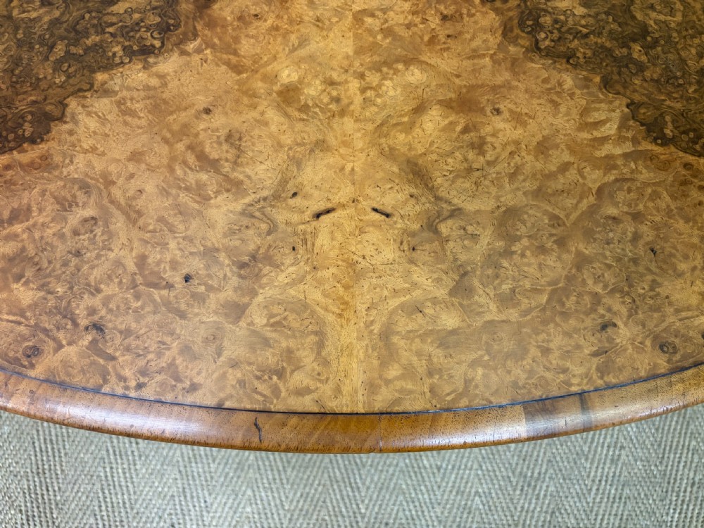 An oval Victorian coffee table crafted from figured burr walnut, featuring a carved four-legged pedestal base and scroll feet. View XI