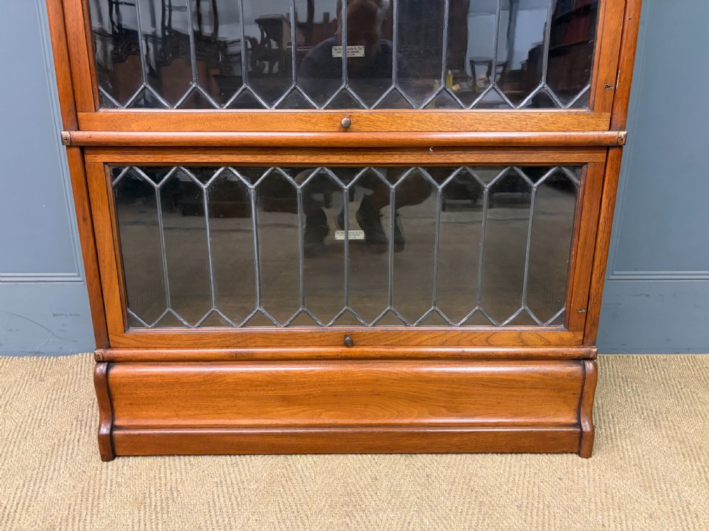 A three-tier walnut Globe Wernicke stacking bookcase featuring leaded glazed doors and a plinth base. View II