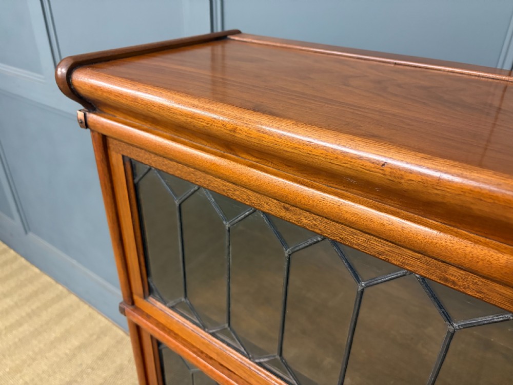 A three-tier walnut Globe Wernicke stacking bookcase featuring leaded glazed doors and a plinth base. View III