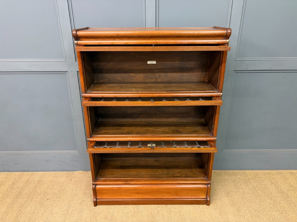 A three-tier walnut Globe Wernicke stacking bookcase featuring leaded glazed doors and a plinth base. View VIII