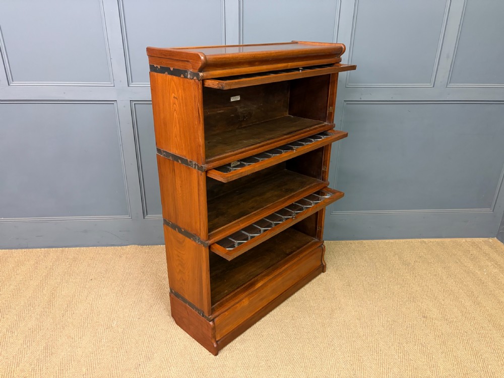 A three-tier walnut Globe Wernicke stacking bookcase featuring leaded glazed doors and a plinth base. View XI