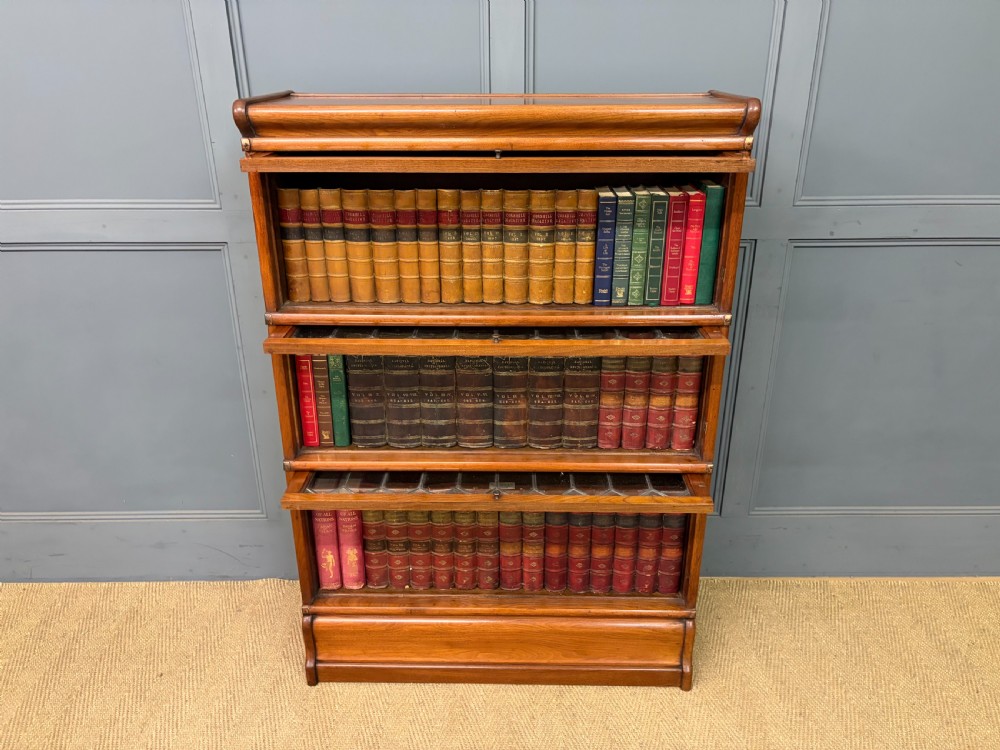 A three-tier walnut Globe Wernicke stacking bookcase featuring leaded glazed doors and a plinth base. View XVI