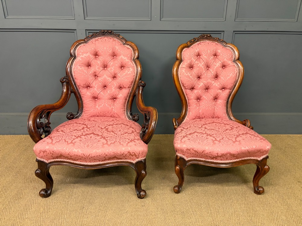 A pair of mid-Victorian carved walnut nursing chairs upholstered in buttoned pink damask fabric with cabriole legs. View II
